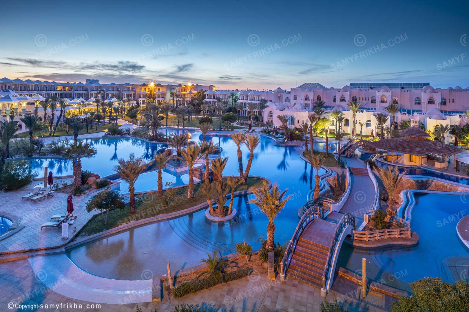 Complexe hôtelier Djerba et grande piscine photographiés au coucher du soleil.