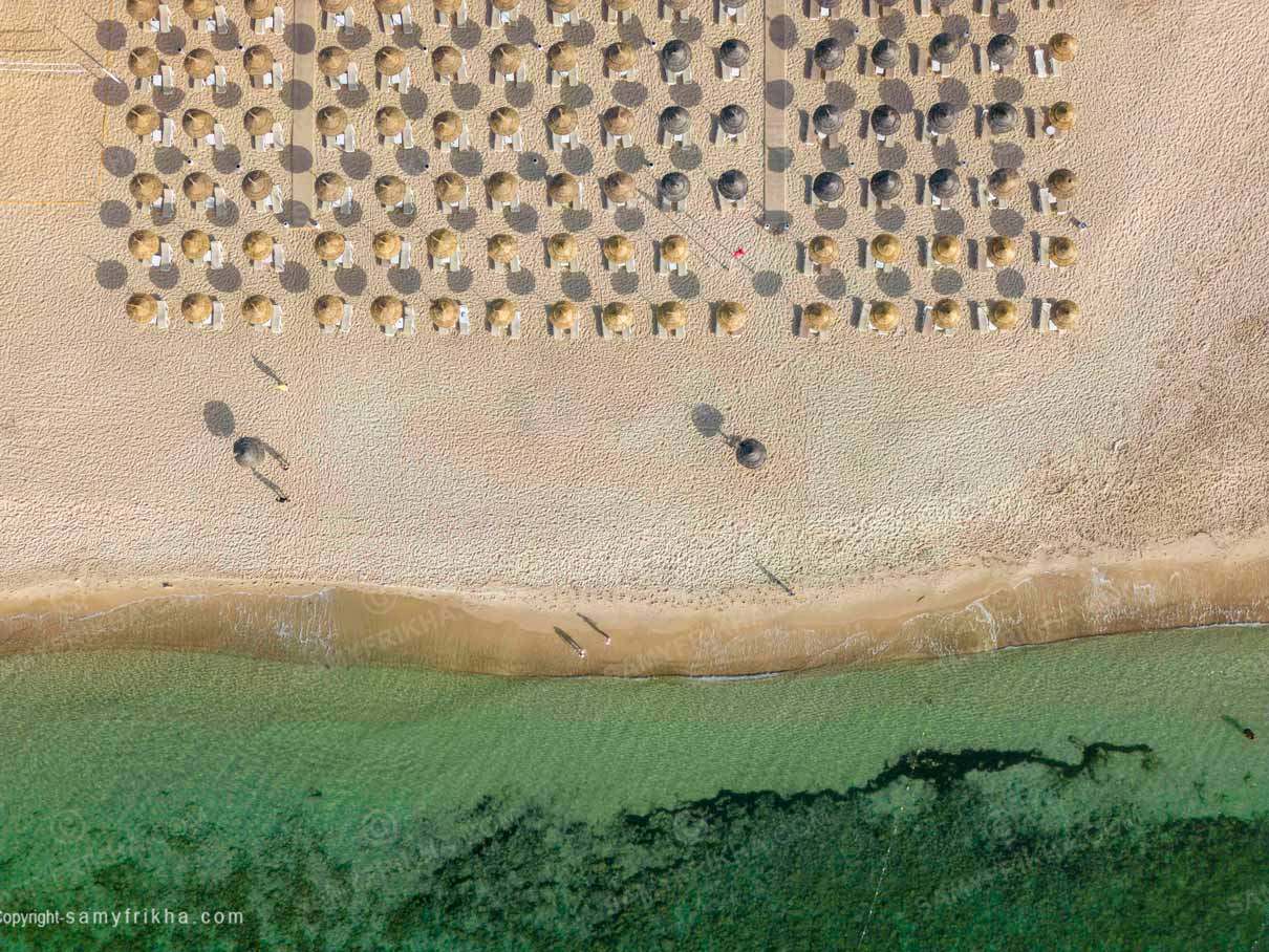 Plage aménagée d'un hôtel avec parasols face à la mer.