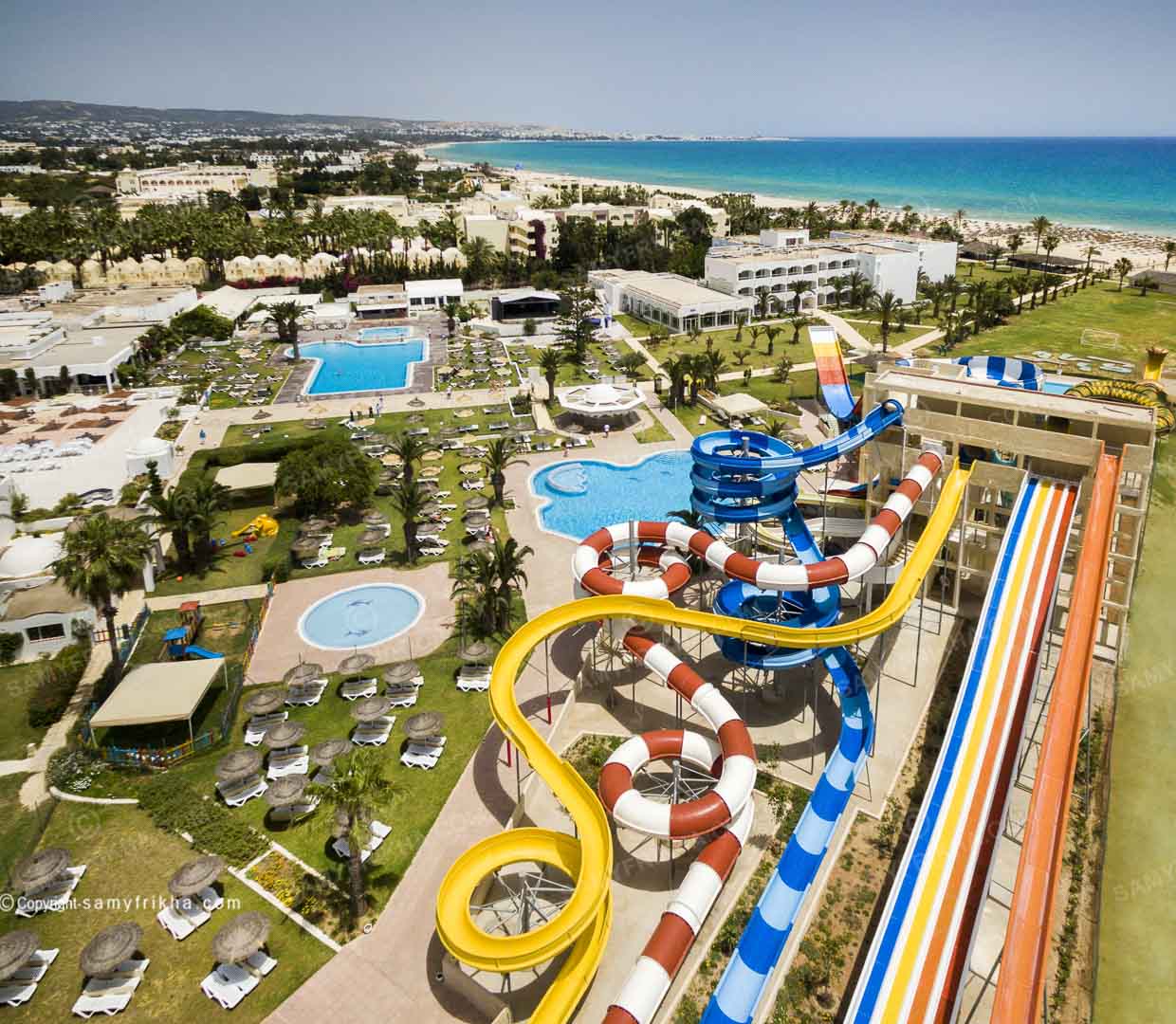 Vue aérienne d'un hôtel avec aquapark, piscines et accès à la plage en Tunisie.