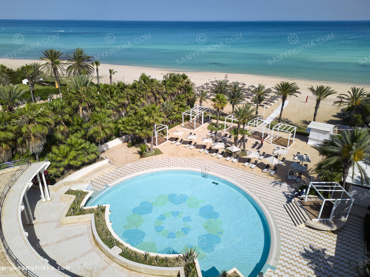 Jardin paysager et piscine d'un hôtel photographiés depuis les airs.