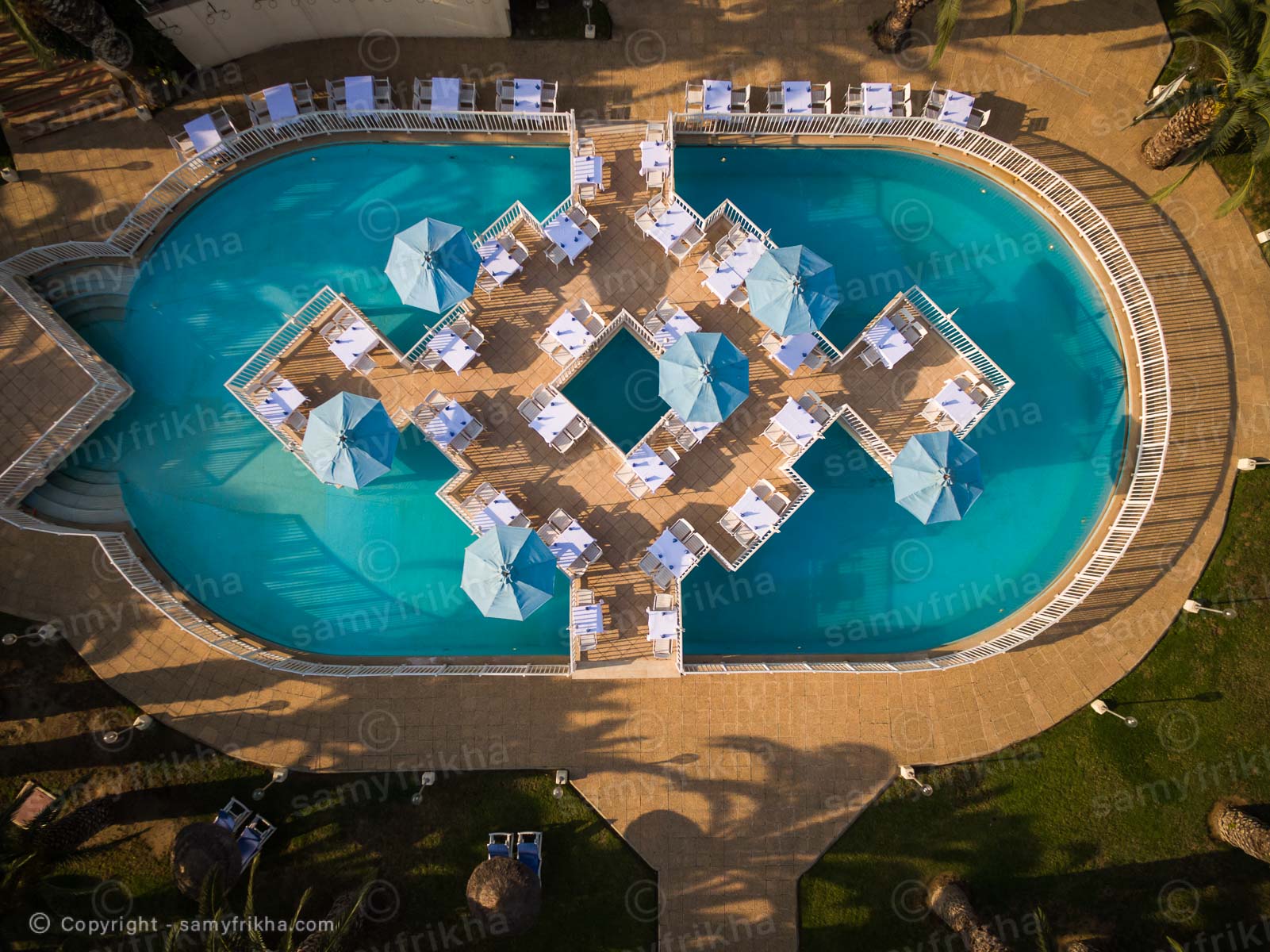 Vue plongeante sur une piscine d'hôtel et son espace de détente.