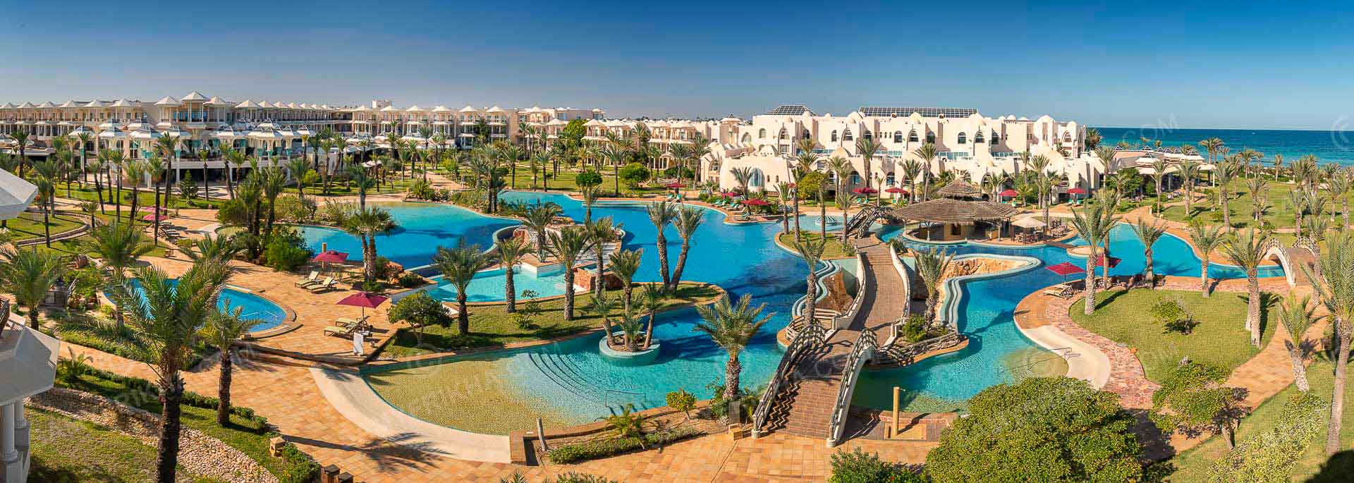 Vue aérienne d'un resort avec piscine, jardins et espaces extérieurs.